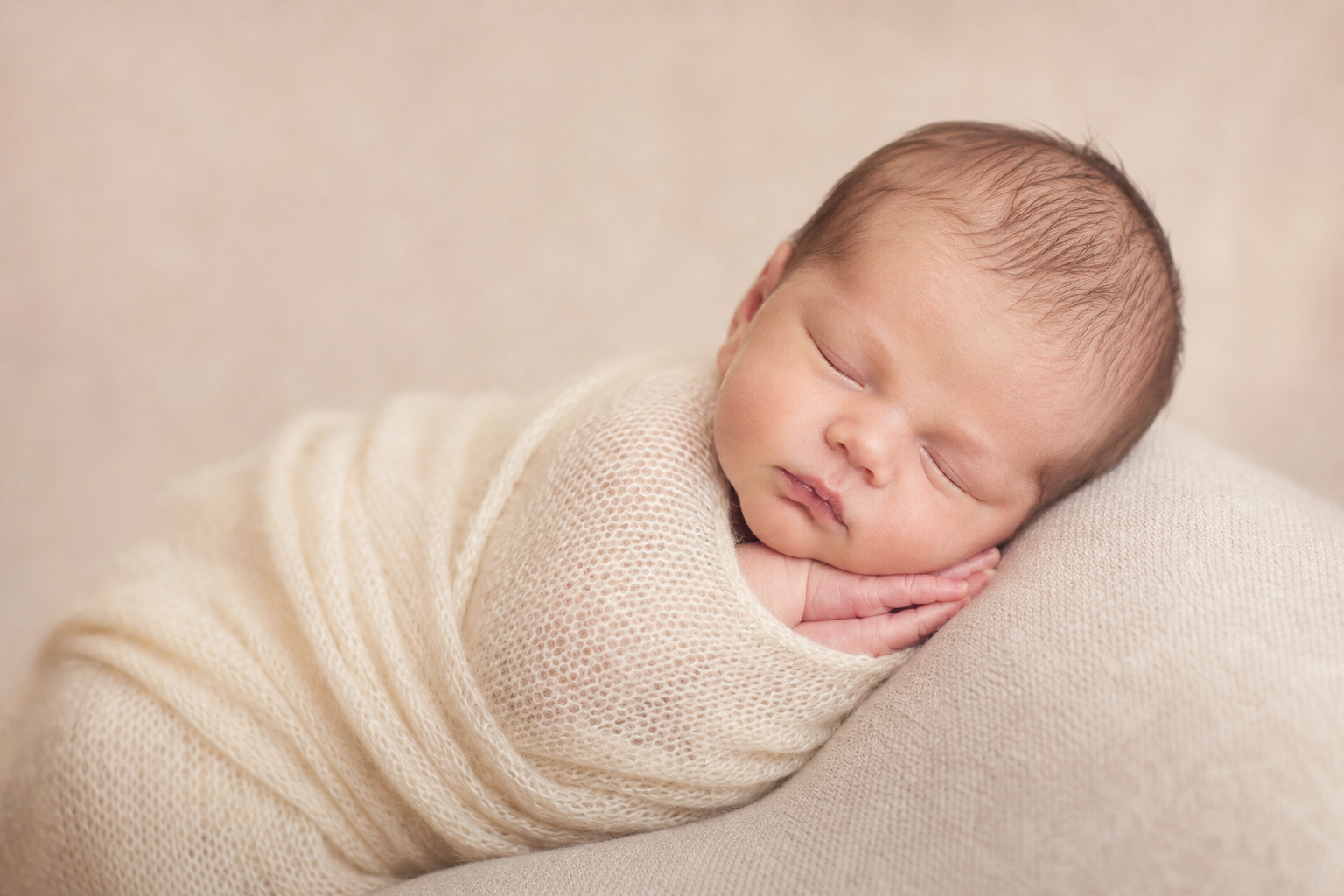 Neonato che dorme avvolto in una morbida copertina, luce delicata